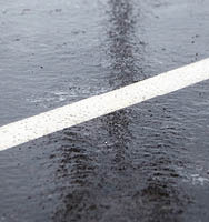 A patch of black ice in a parking lot with white lines.